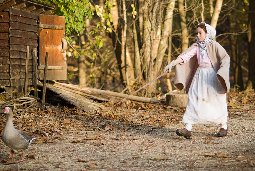 period-attire girl scaring away geese at Claude Moore Colonial Farm