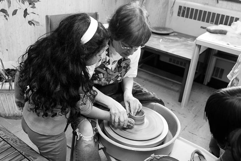 instructor and kid doing wheel pottery