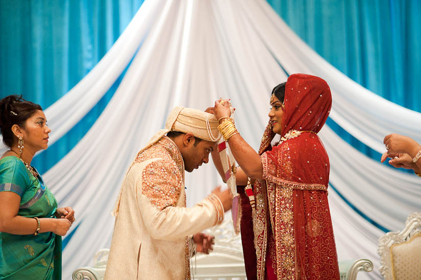 bride puts necklace on groom