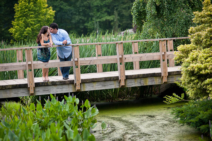 engaged couple kissing on a bridge