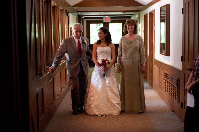 mother and father of the bride walk her down the aisle