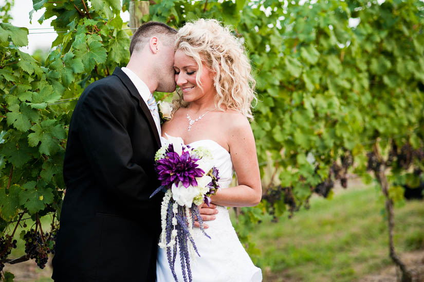 bride and groom in vines at miracle valley vineyard