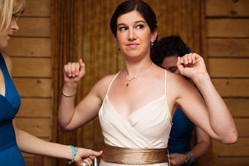 bride putting on dress with brown sash