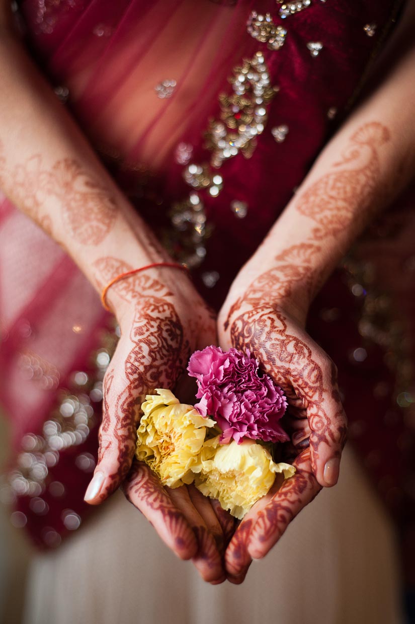 henna on bride's arms, holding flowers