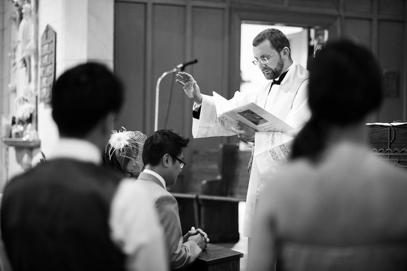 priest holds hand over couple during ceremony