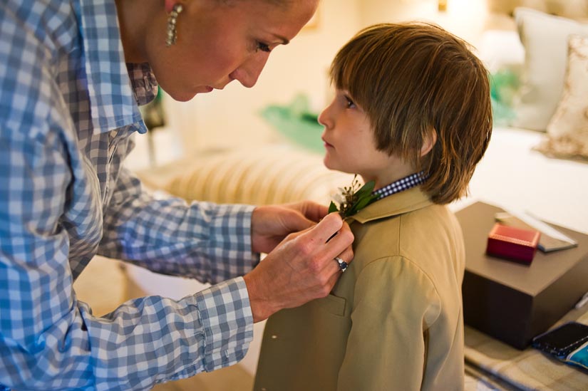bride pins a boutonniere on her son