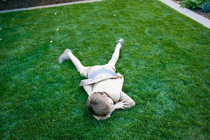 little boy sleeping in grass at the wedding reception
