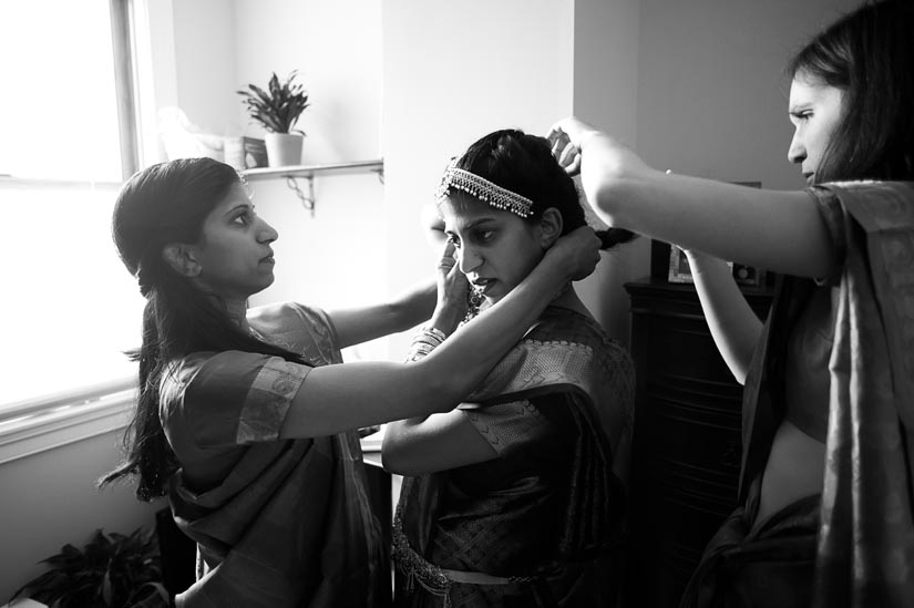 sister and friend help bride get dressed