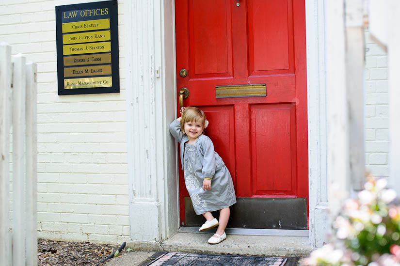 sweet little girl in front of red door in old town alexandria