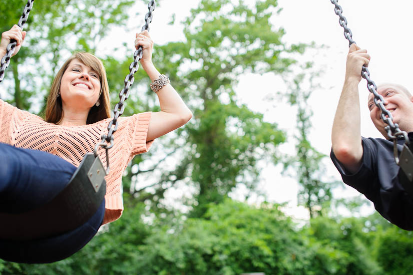 couple on park swings during engagement session