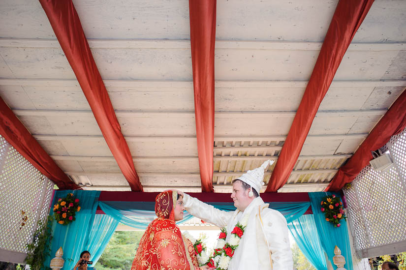groom puts his hand on bride's head at garden falls indian wedding