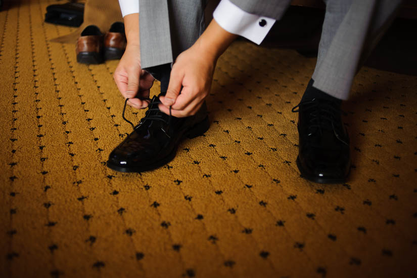 groom tying his shoelaces before his wedding