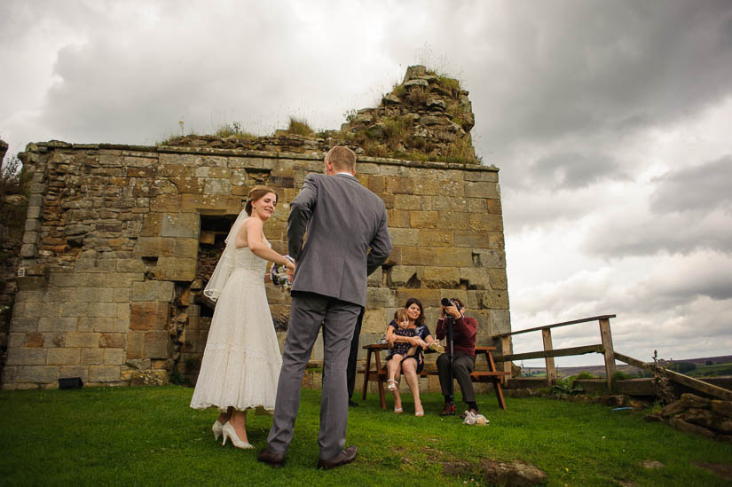 bride and groom in front of castle ruins in north yorkshire