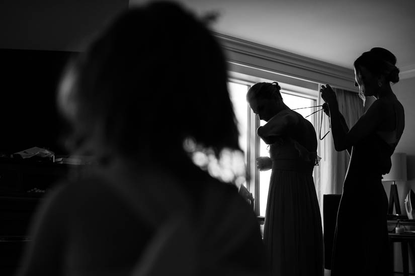 bride helping her sister get dressed before the wedding