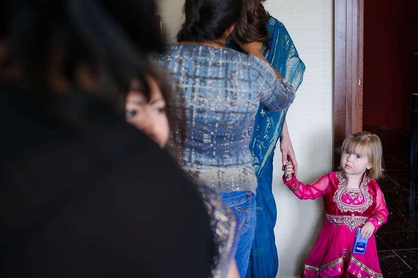 little girl watches bride put on her makeup