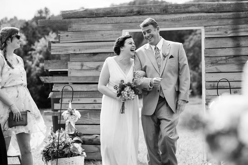 bride and her father laughing as they walk down the aisle