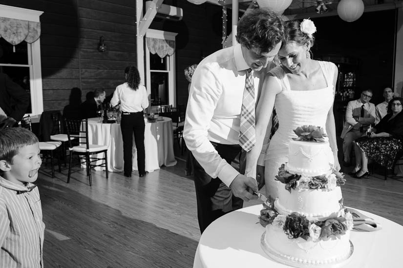 cutting the cake with hungry child looking on