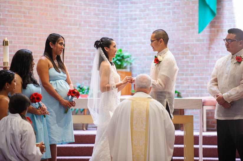bride and groom exchanging rings at our lady of good counsel