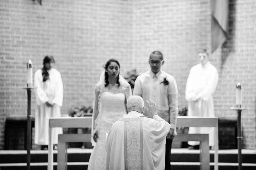priest in focus with couple blurred at wedding ceremony
