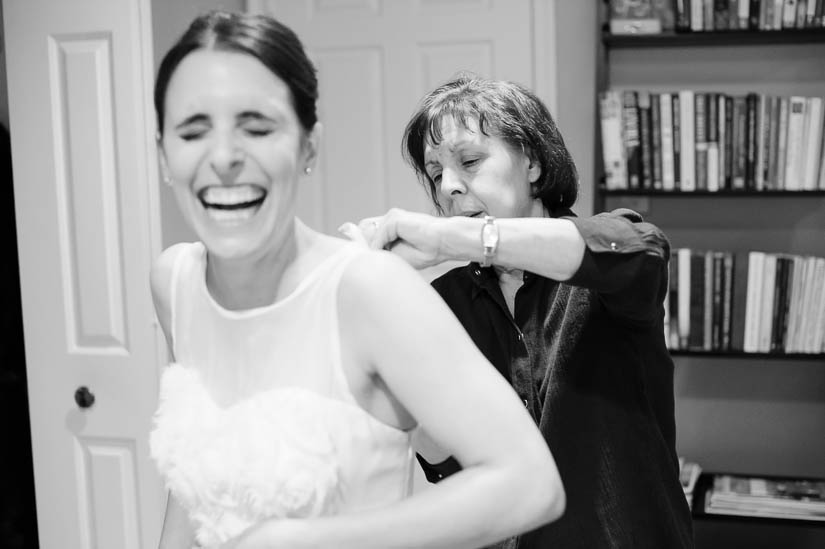 mom helping her daughter dress before the wedding