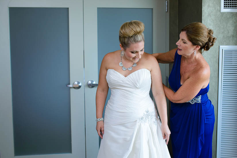 mother of the bride helping her put on the dress