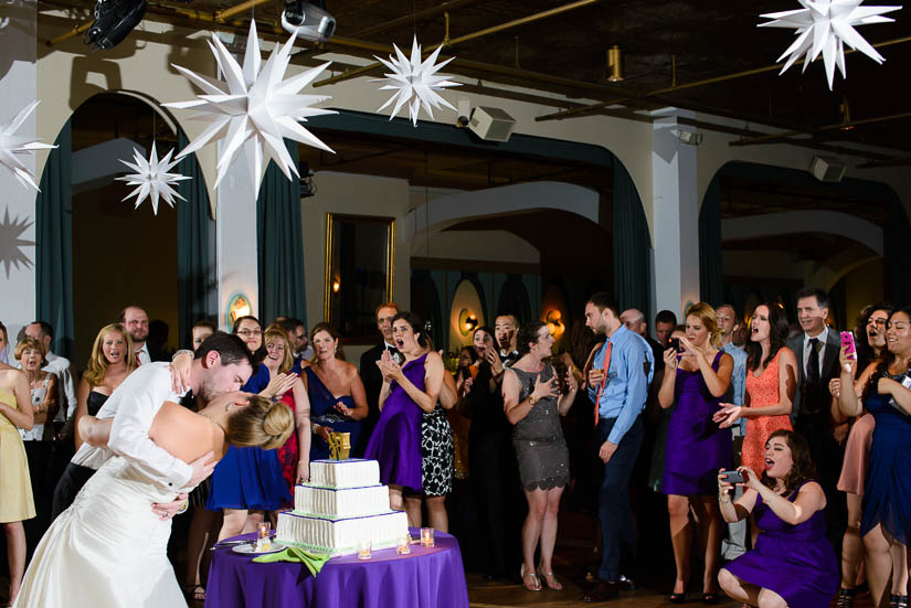 kissing in front of the cake at clarendon ballroom wedding