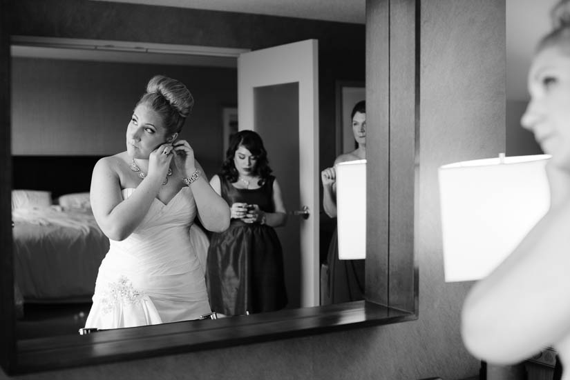 bride putting on earrings while bridesmaids watch